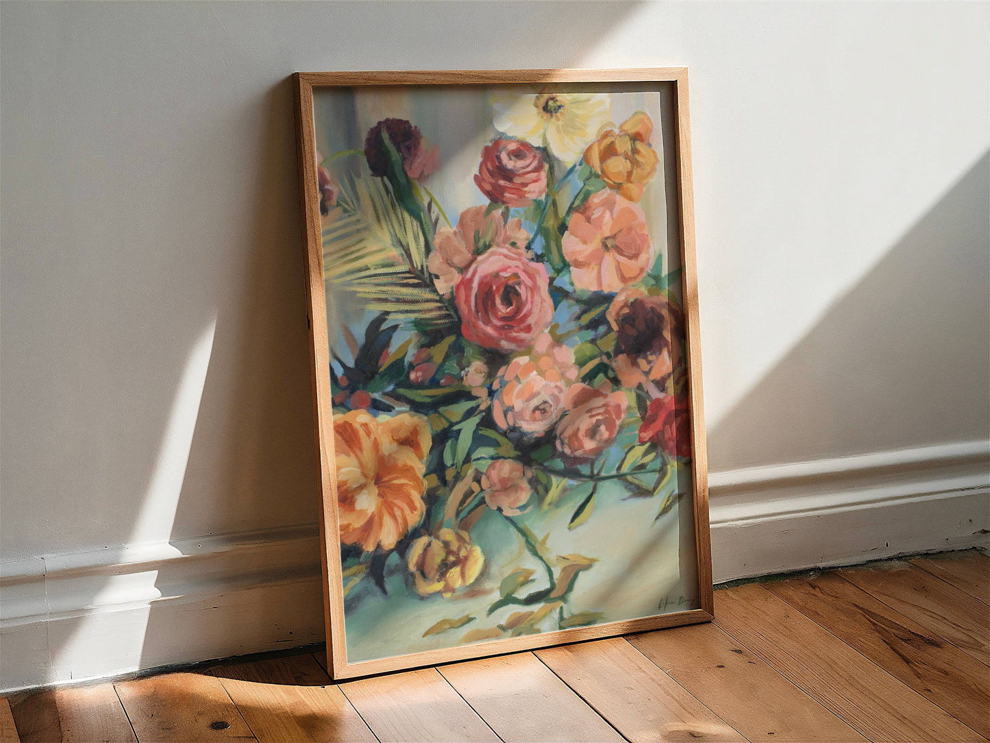 Framed floral botanical painting leaning against a white wall on a wooden floor.