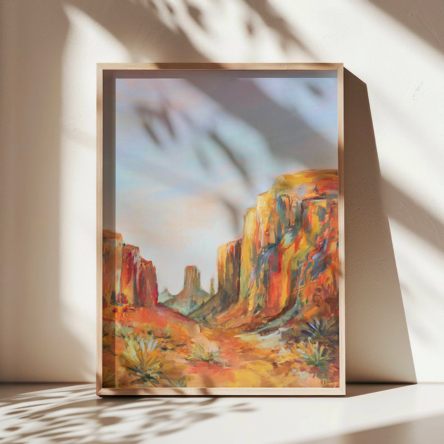 Framed painting of an Arizona desert landscape with orange cliffs and blue sky.