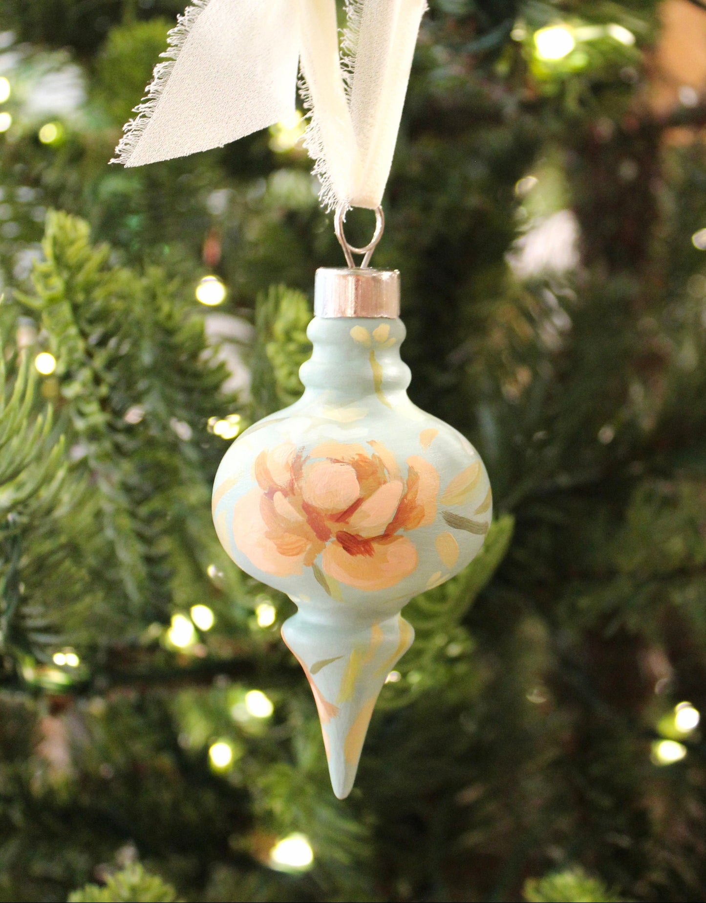 Decorative Christmas ornament with floral design hanging on a tree.