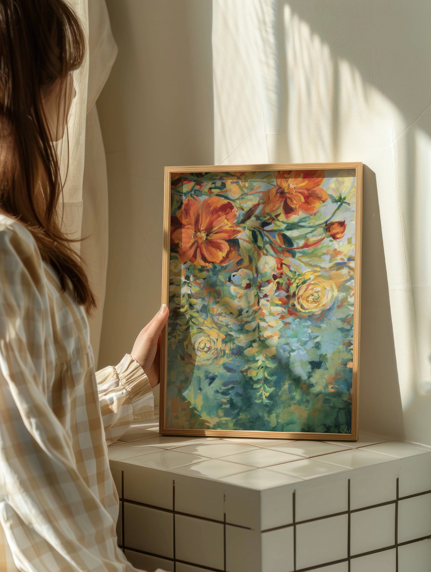 Person holding a framed blue wisteria floral painting in a softly lit room.