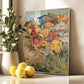 Framed floral painting on a wall with a plant and lemons on a surface below.