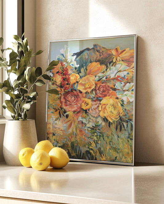 Framed floral painting on a wall with a plant and lemons on a surface below.