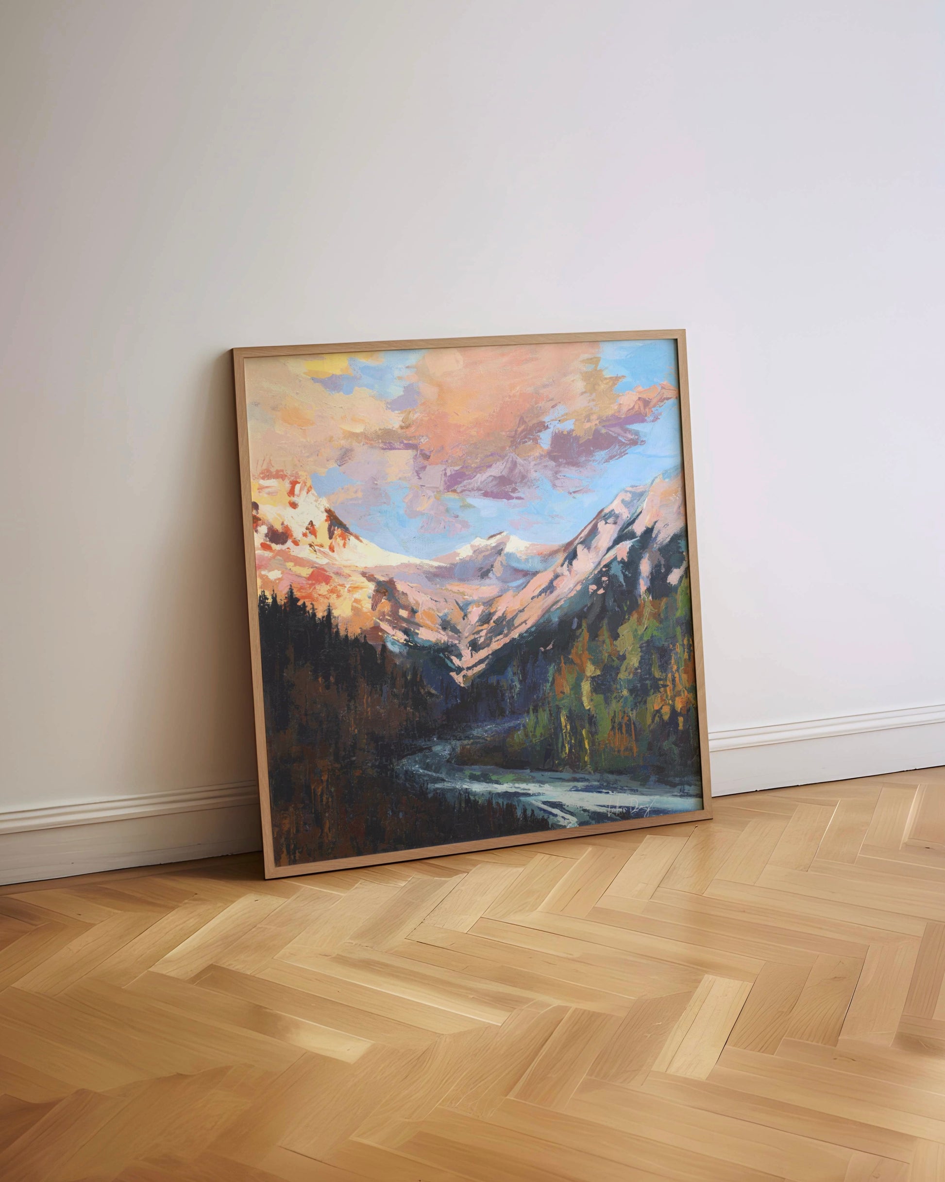 Framed painting of a mountain landscape on a wall with wooden flooring.