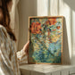Person holding a framed blue wisteria floral painting in a softly lit room.